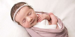 Burgess Hill Photographer photo of baby girl in pink swaddle with headband
