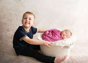 smiling big brother with Baby sister taken by west sussex newborn photographer