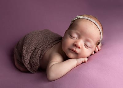 Baby girl with headband sleeping on pink blanket at Burgess Hill photographer Newborn Photoshoot
