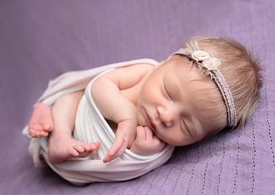 West Sussex newborn photographer best photo of curled up sleeping baby girl with flower headband